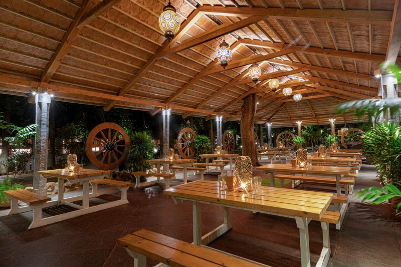 Wooden cottage among green mango trees at Mango Mist Resorts near Bengaluru